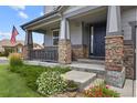 Inviting front porch with stone pillars, gray siding, and colorful flowers adding a welcoming touch at 8182 Grady Cir, Castle Rock, CO 80108