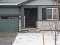 Inviting home exterior showcasing stone accents, covered entryway, a well maintained garage and snow covered landscaping at 1947 S Coolidge Way, Aurora, CO 80018