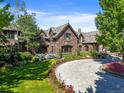 An elegant estate with a brick facade, lush lawns, colorful landscaping, and a circular driveway at 4030 E Forbes Ct, Greenwood Village, CO 80121