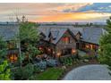 Luxury home featuring a manicured lawn, stone patio, with seating and a colorful mountain sunset at 4030 E Forbes Ct, Greenwood Village, CO 80121