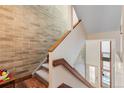 Modern staircase with wooden handrail and exposed brick wall at 680 Crescent Ln, Lakewood, CO 80214