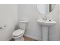 Elegant bathroom featuring a pedestal sink, modern toilet, and decorative mirror at 19120 E 96Th Pl, Commerce City, CO 80022