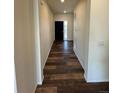 Long hallway featuring stylish wood-look flooring and neutral paint, leading to a modern front door at 914 Peach Leaf Ln, Elizabeth, CO 80107