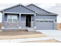 Charming home featuring stone accents, a covered entryway, and a gray garage door at 17170 E 90Th Pl, Commerce City, CO 80022