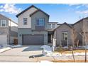 Two-story home featuring a two-car garage, gray siding and a snow-covered lawn at 9982 Wheeling St, Commerce City, CO 80022