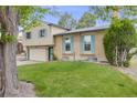 Charming home with a two-car garage, a basketball hoop, and blue shutters and a green lawn in front at 1549 S Evanston St, Aurora, CO 80012