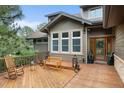 Charming outdoor deck featuring a seating area with a wooden bench and rocking chairs to enjoy wooded views at 1122 Forest Trails Dr, Castle Pines, CO 80108
