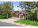 Traditional two-story home with a three-car garage and well-manicured front lawn nestled among mature trees at 1122 Forest Trails Dr, Castle Pines, CO 80108