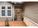 Inviting front entrance featuring a wood door, decorative wreath, and a charming wooden porch with stone accents at 1122 Forest Trails Dr, Castle Pines, CO 80108