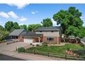 Charming two-story home featuring a well-manicured lawn, brick accents, mature trees, and a welcoming red front door at 7486 S Washington St, Centennial, CO 80122