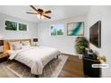 Serene bedroom featuring a cozy bed, warm wood floors, and ample natural light from two windows at 12682 Anhawa Ave, Longmont, CO 80503