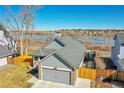 Aerial view of gray home with a fenced yard and a two-car garage near a tranquil lake at 18383 E Union Dr, Aurora, CO 80015