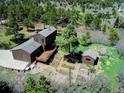 An aerial view of the home, expansive deck, several outbuildings and lush, mature landscaping at 18170 Forest View Rd, Monument, CO 80132