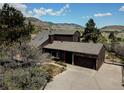 Exterior view of the home, a two-car garage, driveway, and surrounding trees at 18170 Forest View Rd, Monument, CO 80132
