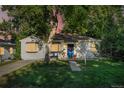 Charming single-story home featuring a lush front yard, mature trees, and inviting front porch seating at 60 Vrain St, Denver, CO 80219