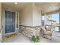 Inviting front porch with stone accents, charming seating, and a welcoming entrance door at 14551 Hudson St, Thornton, CO 80602