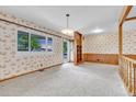 Bright living room featuring a large window, carpeted floors, and classic wallpaper at 8259 Nola Dr, Denver, CO 80221