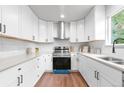 Modern kitchen featuring white cabinets, stainless steel appliances, and hardwood floors at 4257 S Andes Way, Aurora, CO 80013