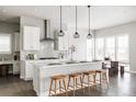 Bright kitchen features white cabinets, stainless steel appliances, and stylish pendant lighting over the island with seating at 533 Red Thistle Dr, Highlands Ranch, CO 80126