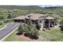 Aerial view of an elegant home with a three-car garage, mature landscaping, and a gorgeous mountain backdrop at 1272 Nightfire Cir, Castle Rock, CO 80104