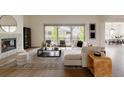 Bright living room features a cozy fireplace, large windows, and stylish, neutral furniture at 6608 S White Crow Ct, Aurora, CO 80016