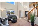 Bright living room with soaring ceilings, staircase, and ample natural light from large windows at 5481 E 117Th Ave, Thornton, CO 80233