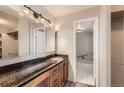 Well-lit bathroom featuring a granite countertop vanity, wood cabinets and a shower-over-tub with modern tile at 955 Eudora St # 1107, Denver, CO 80220