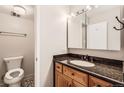 Cozy bathroom with a granite-topped vanity, warm wood cabinets, and a toilet in a private space at 955 Eudora St # 1107, Denver, CO 80220