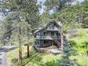 Gorgeous two-story home nestled in the trees, featuring a wraparound deck and stone accents at 30221 Marge Ln, Evergreen, CO 80439