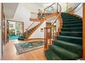 Grand foyer featuring a split staircase, wooden banisters, green carpet runner, hardwood floors and high ceilings at 1332 Meadow Trl, Franktown, CO 80116