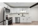 Bright kitchen featuring stainless steel appliances, white cabinets, and eye-catching herringbone tile backsplash at 3470 S Poplar St # 401, Denver, CO 80224