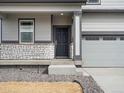 Inviting front entrance with stone accents, a covered porch, and a convenient two-car garage at 8820 Sedalia St, Commerce City, CO 80022