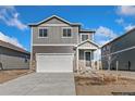 Two-story home with gray wood and stone accents, attached garage, and freshly landscaped yard at 864 Leeward St, Lochbuie, CO 80603