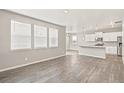 Open-concept living room with gray vinyl floors, bright windows, and neutral paint at 864 Leeward St, Lochbuie, CO 80603