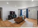 Comfortable living room showcasing hardwood floors, recessed lights, modern furnishings, and a bright window with blue curtains at 1670 Oakland St, Aurora, CO 80010