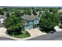Aerial view of a blue home with a three-car garage surrounded by mature trees at 12535 S Beaver Creek Way, Parker, CO 80134