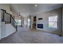 Spacious living room boasting a fireplace with brick surround and staircase with dark metal railings at 12535 S Beaver Creek Way, Parker, CO 80134
