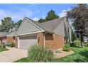 View of home featuring brick and horizontal siding, manicured lawn and gardens, along with a two-car garage at 7183 S Poplar St, Centennial, CO 80112