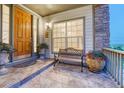 Inviting front porch featuring a wooden door, stone accents, and a bench with decorative potted plants at 12350 Turquoise Terrace St, Castle Pines, CO 80108