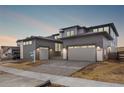 Modern two-story home with gray siding, stone accents, a two-car garage, and professionally landscaped yard at 6529 Still Pine Cir, Castle Pines, CO 80108