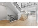 Spacious foyer showcasing an open floor plan, light wood floors and staircase with modern black metal railings at 6529 Still Pine Cir, Castle Pines, CO 80108