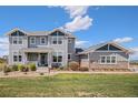Inviting two-story home with gray siding and a covered front porch with stone accents and landscaped yard at 7692 Weaver Cir, Castle Rock, CO 80104