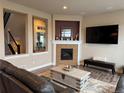 Cozy living room with stone fireplace, dark leather furniture and modern decor at 7692 Weaver Cir, Castle Rock, CO 80104