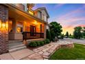 Inviting front porch with stone steps, brick pillars, and a manicured front yard showcasing lush green bushes at 7038 Russell Ct, Arvada, CO 80007