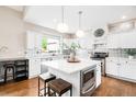 Bright kitchen with white cabinets, stainless steel appliances, large center island and elegant pendant lighting at 7038 Russell Ct, Arvada, CO 80007