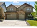 Two-story home boasts a stone facade, attached three-car garage, and a covered porch at 7949 S Elk Way, Aurora, CO 80016