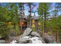 Beautiful exterior of a multi-level home surrounded by lush greenery, boulders and slight snow cover at 3816 Spring Valley Trl, Evergreen, CO 80439