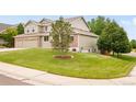 Two-story home featuring a well-manicured lawn with a mature tree at 1477 Serene Dr, Erie, CO 80516