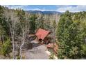 Aerial view of a cozy cabin with a detached garage surrounded by lush forest and mountain views at 9530 Aspen Ln, Conifer, CO 80433