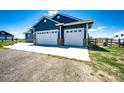 Spacious three-car garage with white doors and brick base, offering ample parking and storage at 59466 E Commanche Way, Strasburg, CO 80136